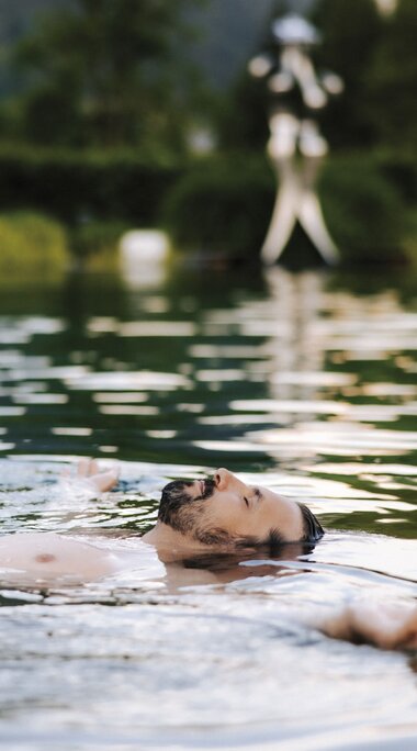 Mann relaxt im Thermalwasser Badesee der Alpentherme | © Alpentherme Gastein/Paul Bauer