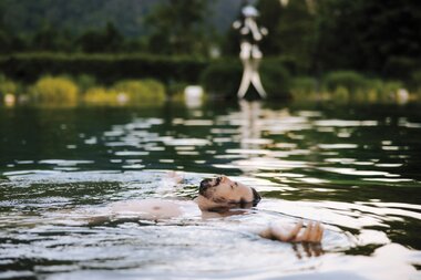 Mann relaxt im Thermalwasser Badesee der Alpentherme | © Alpentherme Gastein/Paul Bauer
