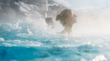 Paar geniesst Wassersprudel im Thermalwasser outdoor | © Alpentherme Gastein/Marktl Photography